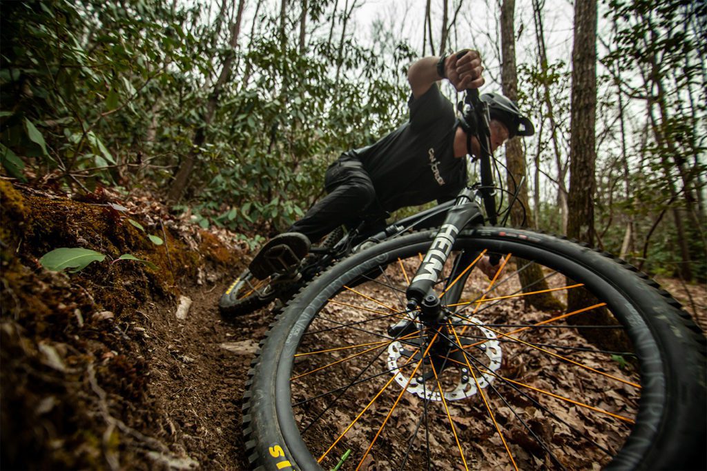 Man hitting berm with Cane Creek Jersey and HELM MKII Fork